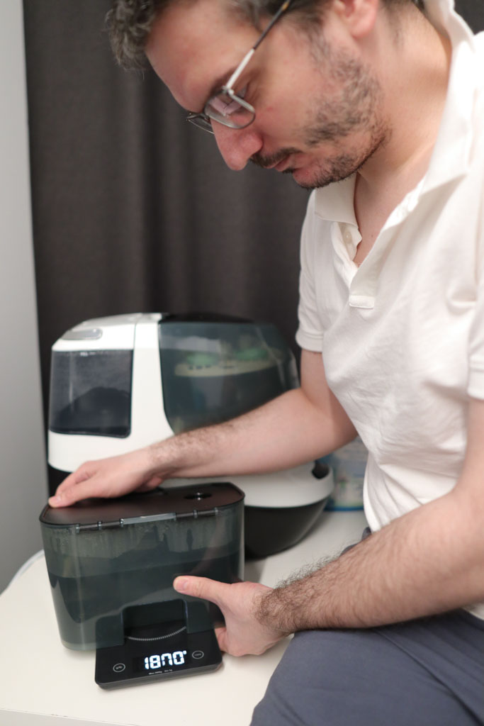 A photo of Dim Nikov, Dad's Picks editor, weighing the dirty water tank of a baby bottle washer for a review.